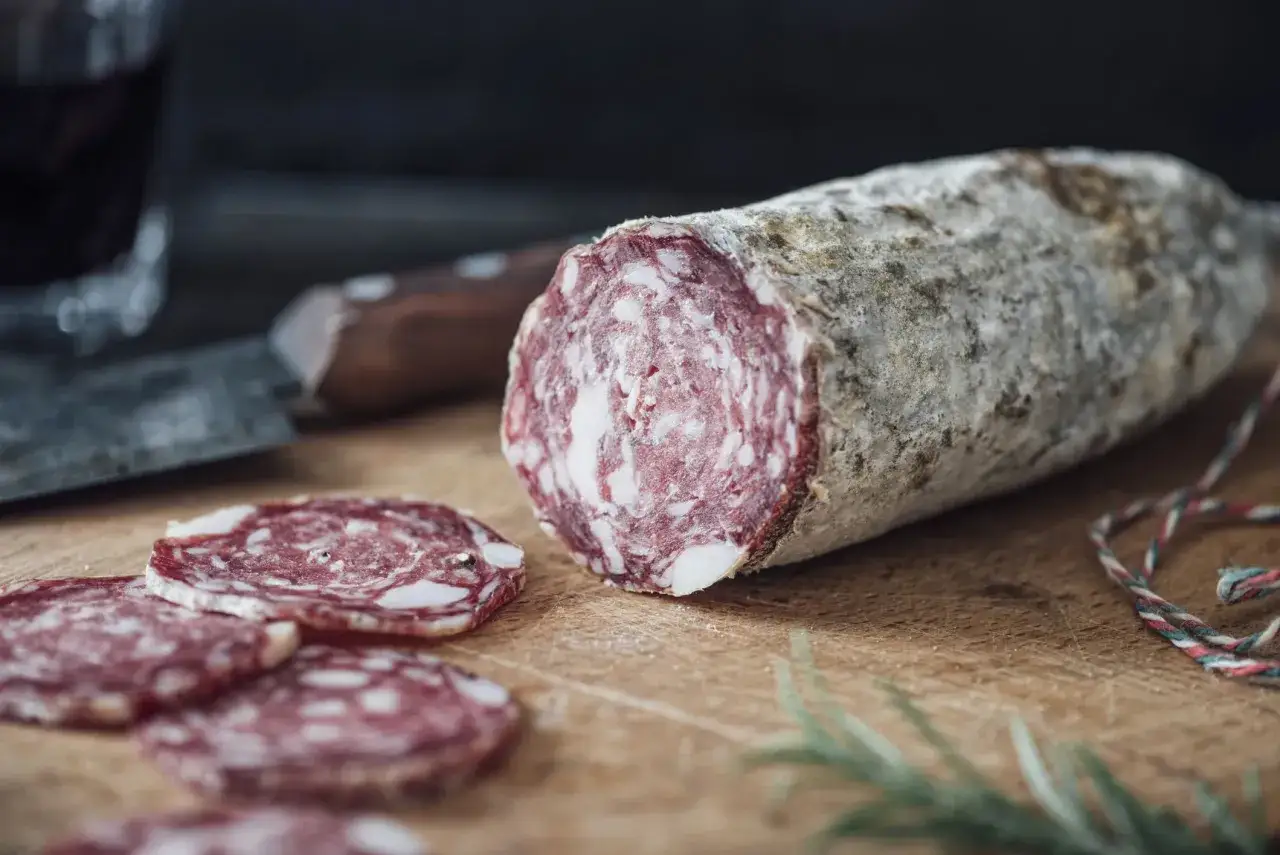 Ein Anschnitt einer Salami auf einem Holzbrett. Die Frage