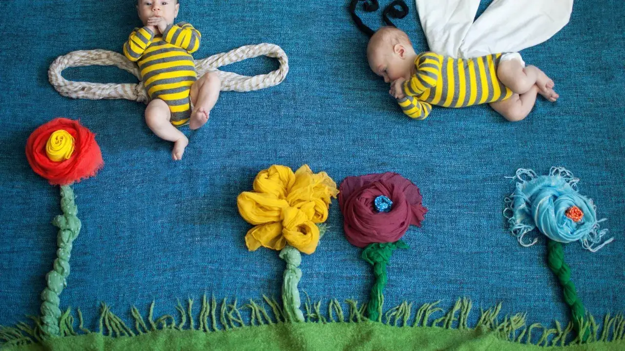 Zwei Babys in Bienenkost&uuml;men, umgeben von Stoffblumen. Ein s&uuml;&szlig;er Anblick, der an das honig essen beim stillen erinnert.