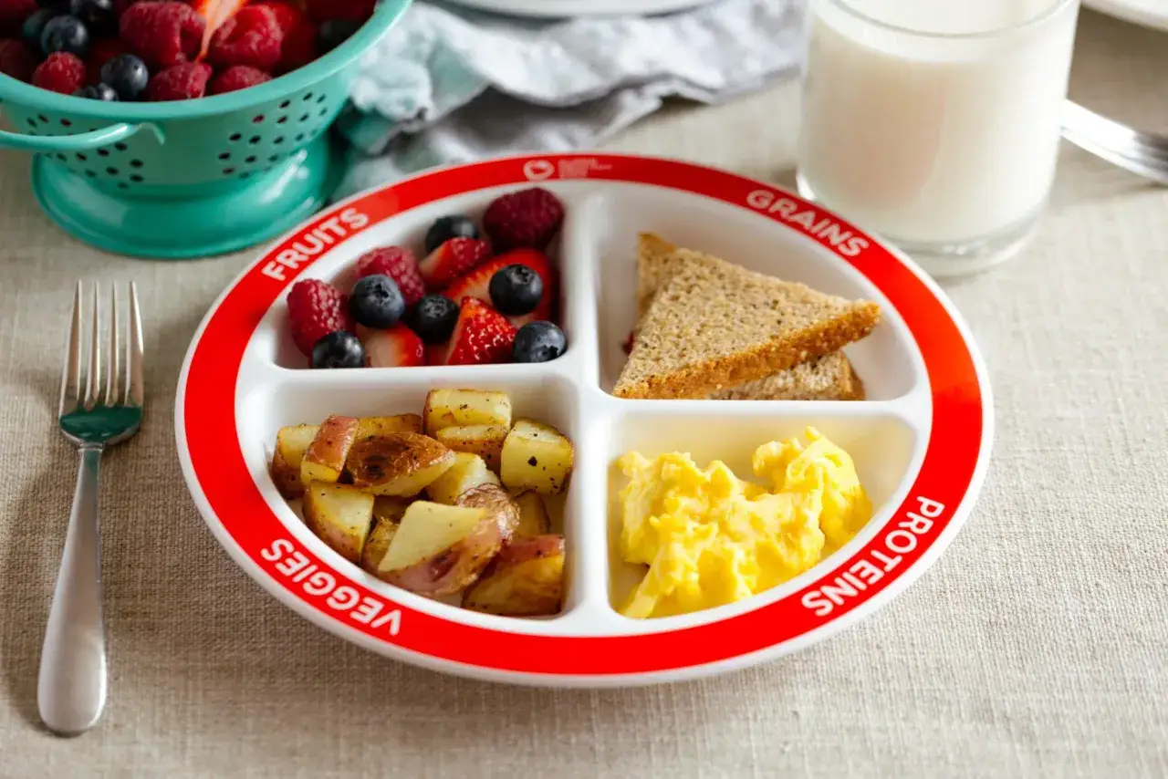 Gesundes Frühstück für ein Kleinkind 2 Jahre: Rührei, Kartoffeln, Toast und Beeren.