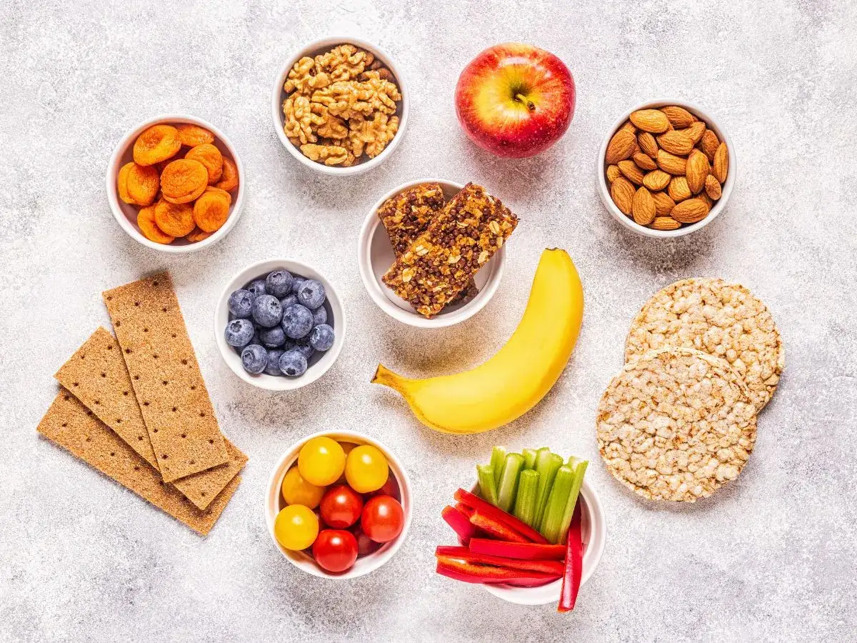 Gesunde Snacks für Energie in der Stillzeit: Nüsse, Trockenfrüchte, Beeren, Banane, Apfel, Gemüsesticks und Vollkorncracker.