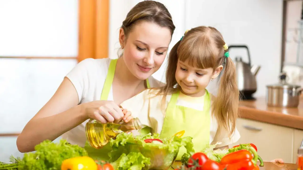 Mutter und Kind bereiten gemeinsam einen Salat zu. Ein positives Beispiel für das Essverhalten von Kindern, das gesunde Ernährung fördert.