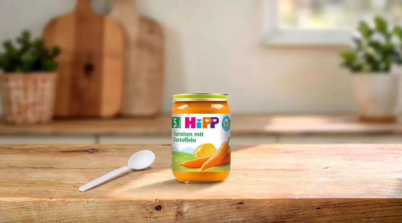 Hipp Karotten mit Kartoffeln Glas, ideal für den Start der Beikost ab 6 Monaten. Löffel liegt bereit.