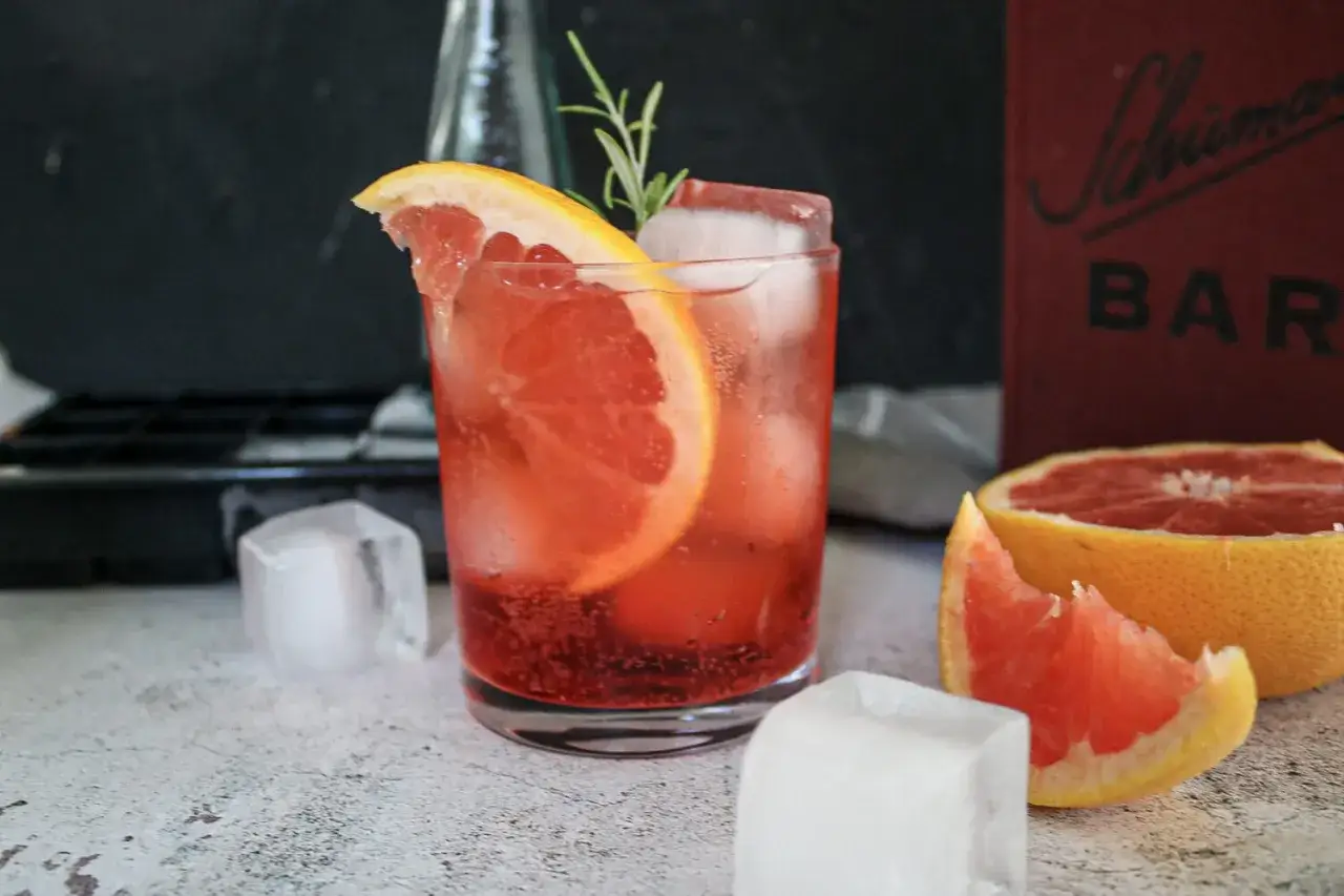 Erfrischender bitter lemon Drink mit Grapefruit und Rosmarin, perfekt f&uuml;r die Stillzeit. Eisw&uuml;rfel und eine halbe Grapefruit runden das Bild ab.