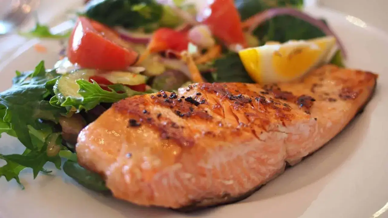 Gebratener Lachs mit Salat und Zitrone. Viele denken, das sei ein verbotenes Lebensmittel in der Stillzeit, aber es ist eine gute Proteinquelle.