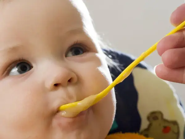 Ein Baby wird mit einem gelben Löffel gefüttert. Der Brei ist warm, perfekt zum babybrei warm halten.