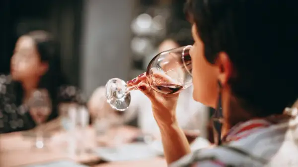 Frau trinkt Rotwein. Die Frage "darf man beim stillen Alkohol trinken?" beschäftigt viele.
