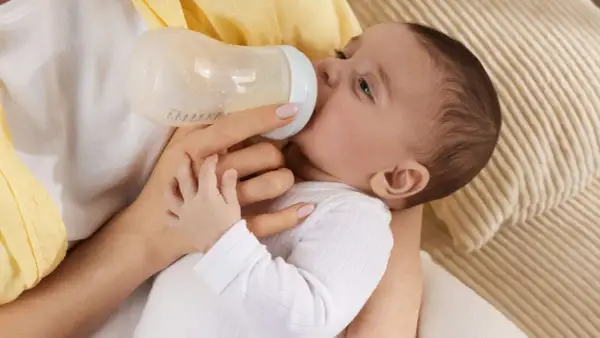 Baby trinkt aus Flasche, vielleicht wegen Wachstumsschub. Es spuckt danach mehr, aber das ist normal.