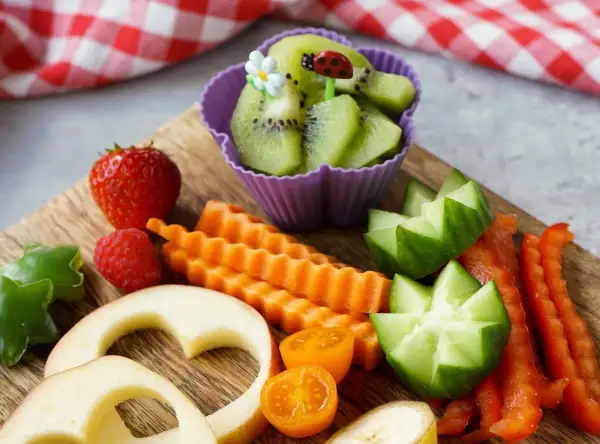 Buntes Obst und Gemüse für ein Baby von 1 Jahr: Erdbeeren, Kiwi, Karotten, Gurken, Paprika, Apfelherzen.