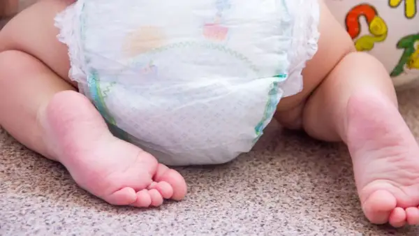 Babyfüße neben einer Windel. Bei Windeldermatitis hilft schnell eine gute Pflege.