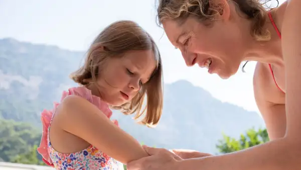 Mutter untersucht den Arm ihres Kindes nach einem Wespenstich.